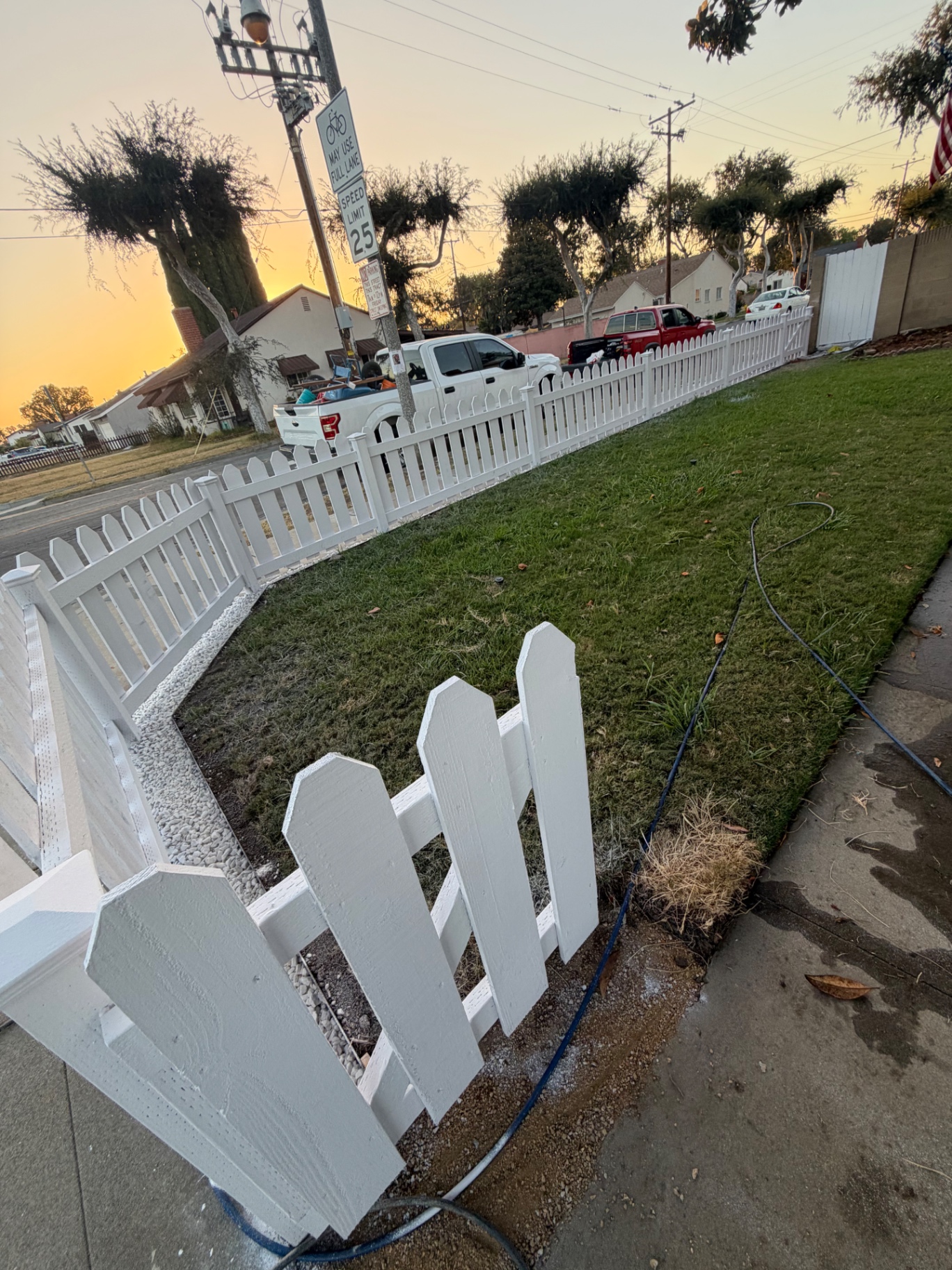 Front yard lawn edged by a freshly installed white picket fence