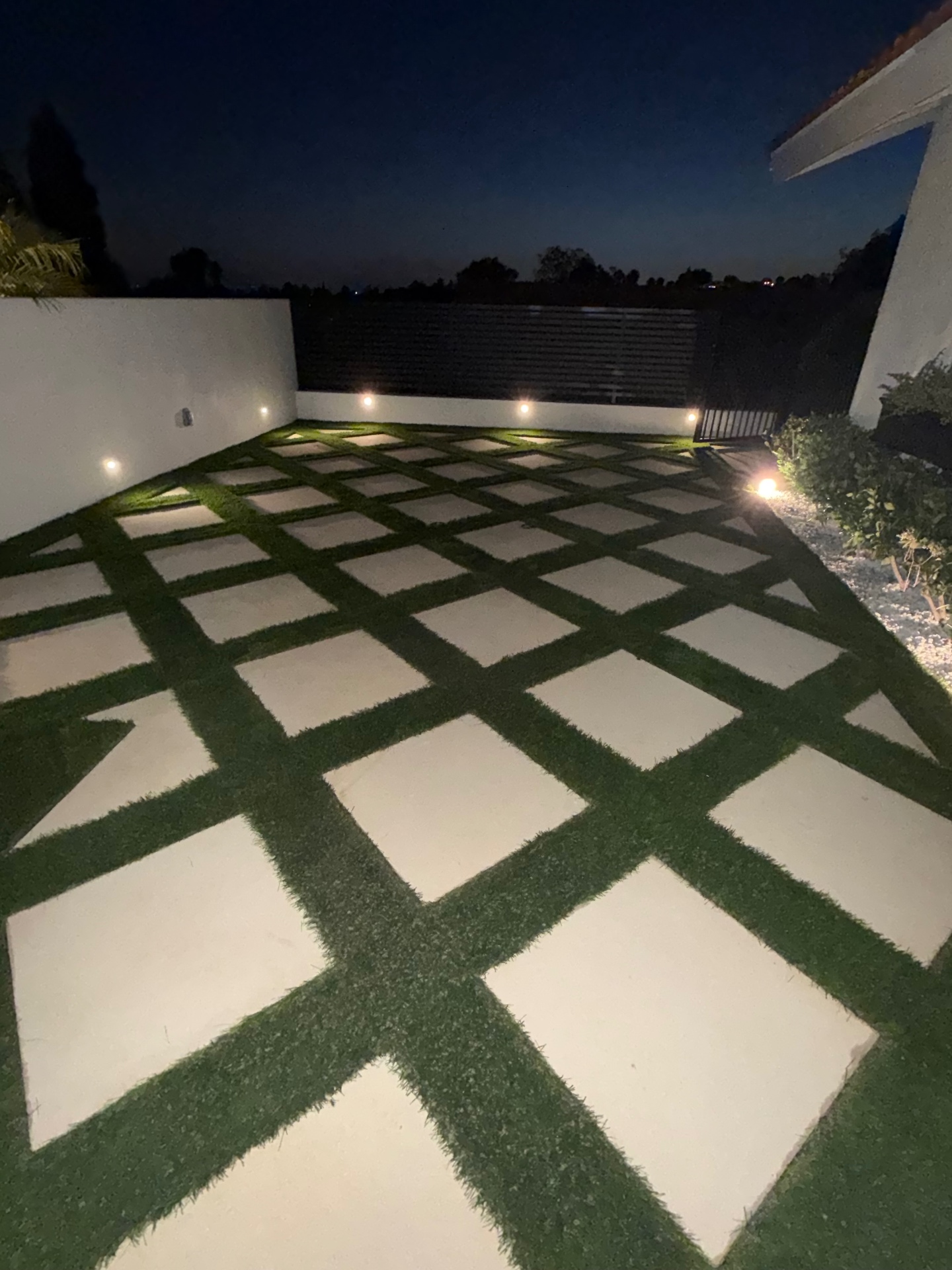 Paver and turf patio lit by low-voltage landscape lighting at night