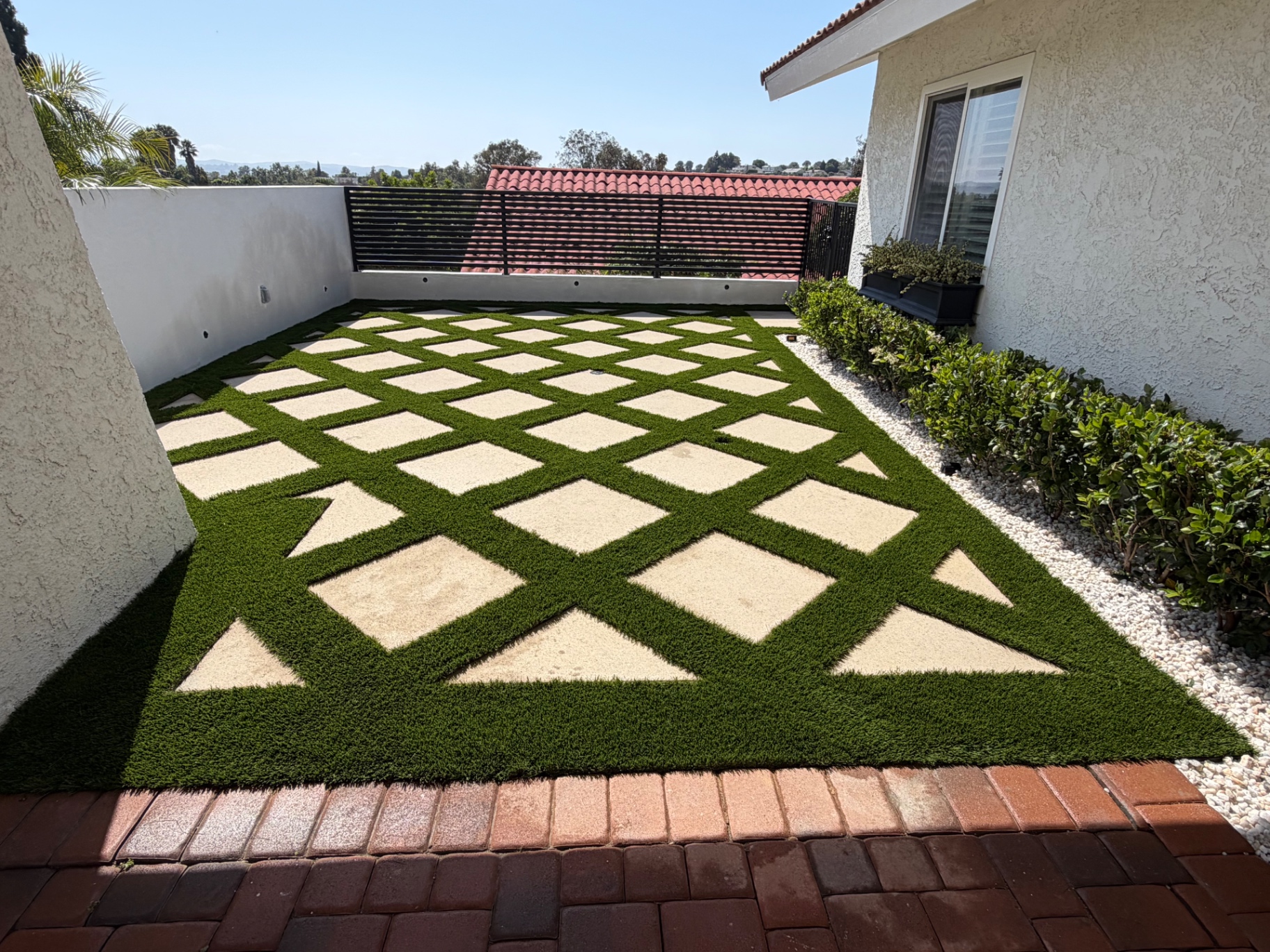 Diamond-pattern paver and artificial turf courtyard with gravel border